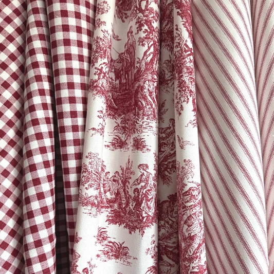 a close-up view of a collection of fabric swatches, showcasing a variety of patterns and colors. The swatches include a red and white checkered fabric, a red and white striped fabric, and a red and white floral fabric. The fabric swatches are arranged in a row, creating a visually appealing display of different patterns and textures.
