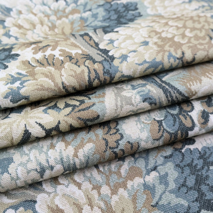 a close-up view of a fabric with a floral pattern in shades of blue, green, and beige. The fabric appears to be folded or rolled, revealing the intricate design and texture of the material.