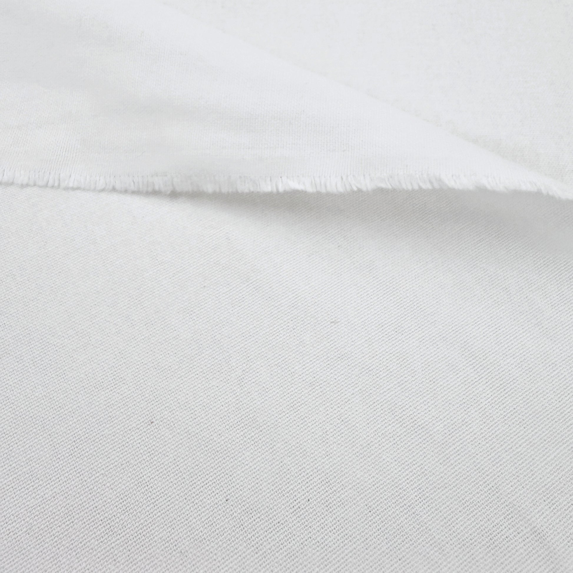 A close-up view of a white fabric, possibly cotton, with a slightly wrinkled texture.