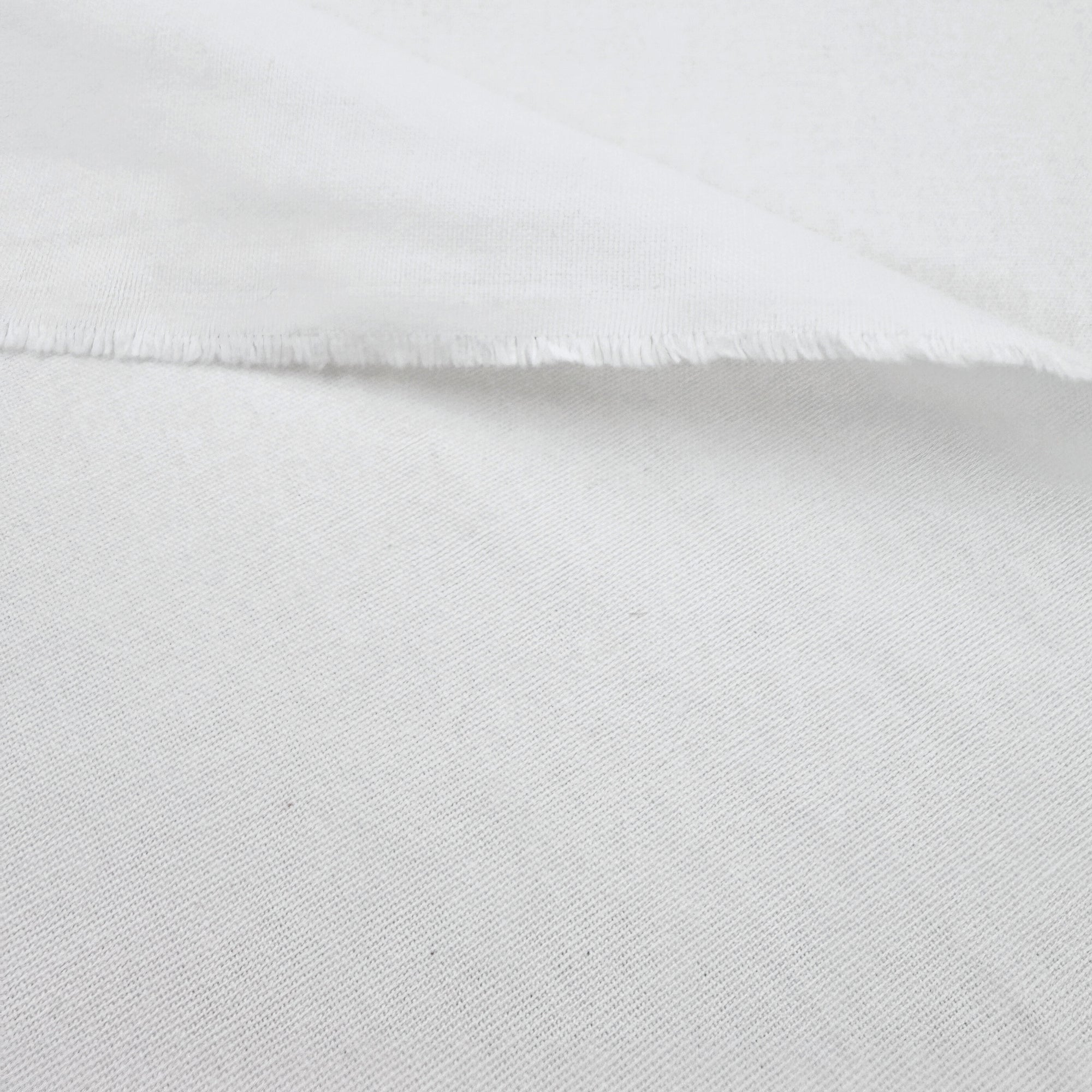 A close-up view of a white fabric, possibly cotton, with a slightly wrinkled texture.