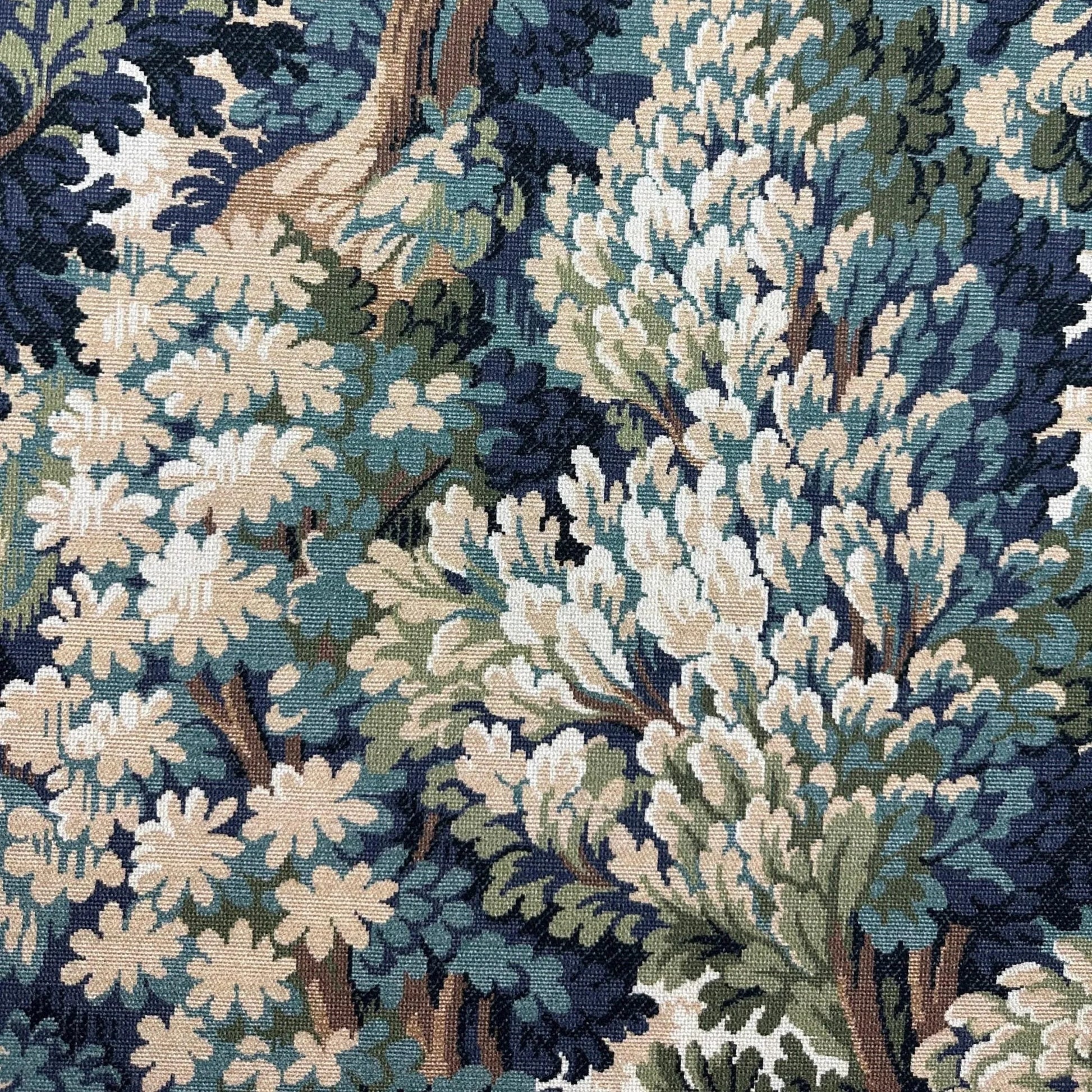 The image is a close-up of a detailed tapestry or fabric with a complex pattern of various shades of blue, green, and white. The pattern features a variety of textures and shapes, including leaves, flowers, and branches, creating a visually striking and intricate design.