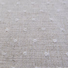a close-up view of a beige fabric with small white dots or circles scattered across it, creating a textured and patterned appearance.