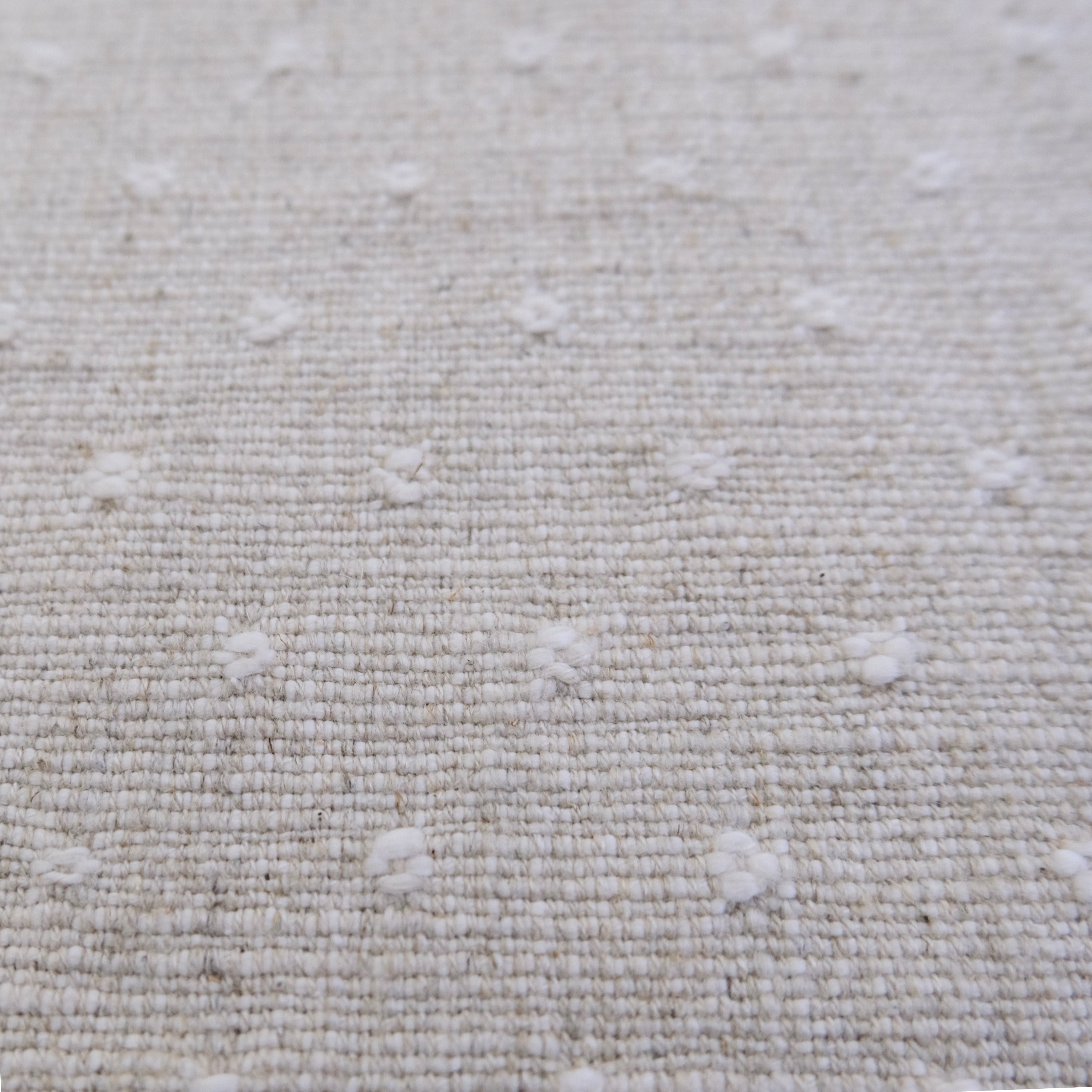 a close-up view of a beige fabric with small white dots or circles scattered across it, creating a textured and patterned appearance.