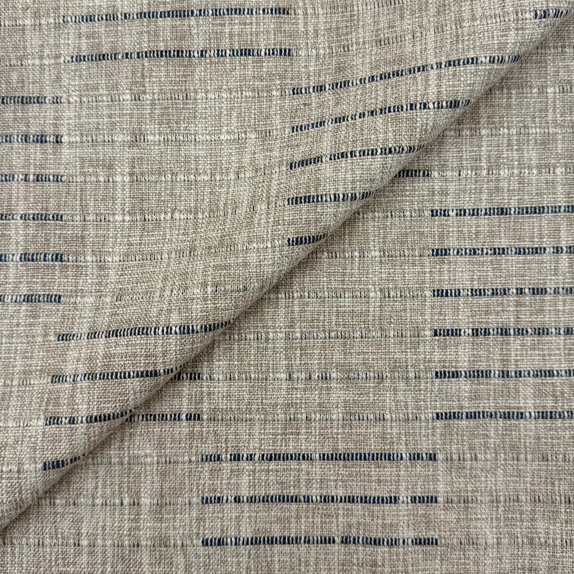 a close-up view of a fabric with a striped pattern in shades of gray and blue. The fabric appears to be made of a woven material, with the stripes varying in size and spacing. The image does not contain any text or other discernible objects or actions.