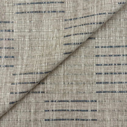 a close-up view of a fabric with a striped pattern in shades of gray and blue. The fabric appears to be made of a woven material, with the stripes varying in size and spacing. The image does not contain any text or other discernible objects or actions.