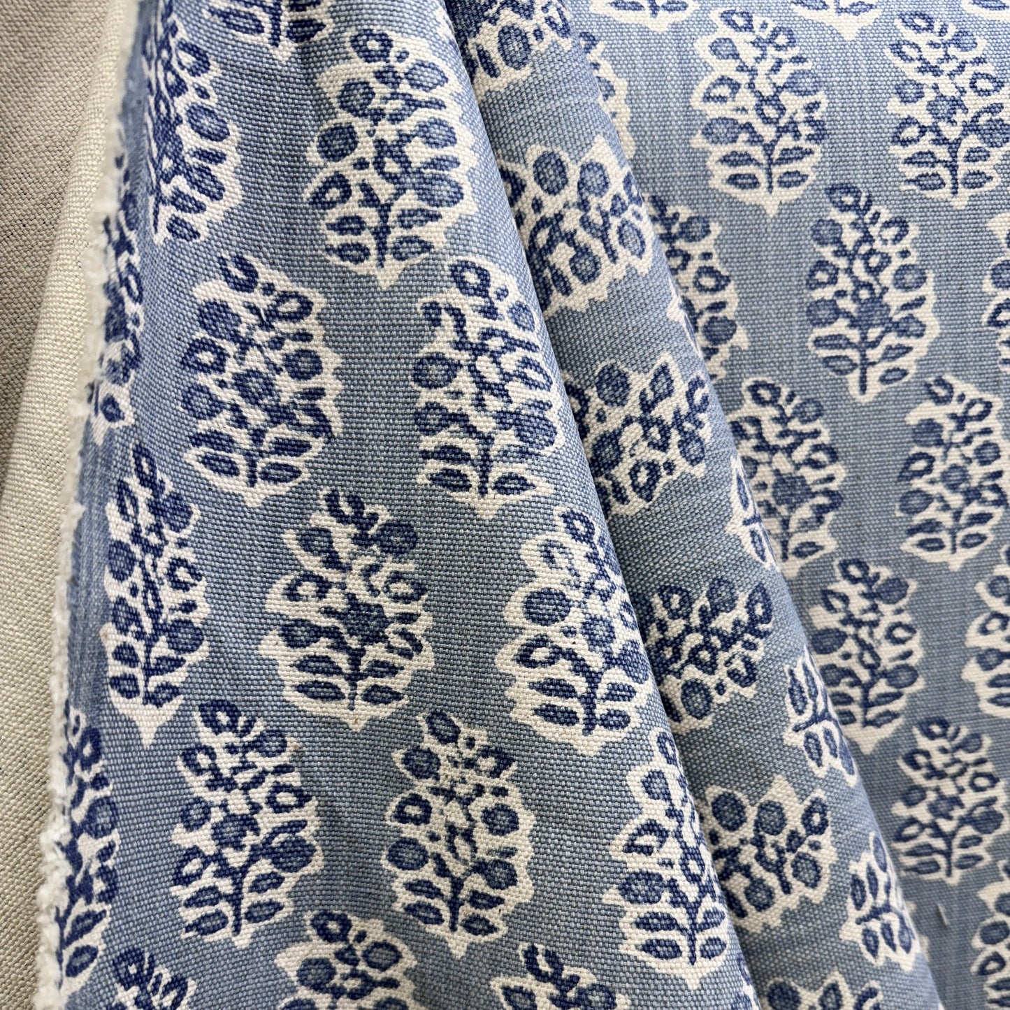 Blue floral medallion fabric in soft drape showing repeating block print pattern