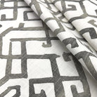 a close-up view of a fabric with a repeating pattern of geometric shapes in shades of gray and white.