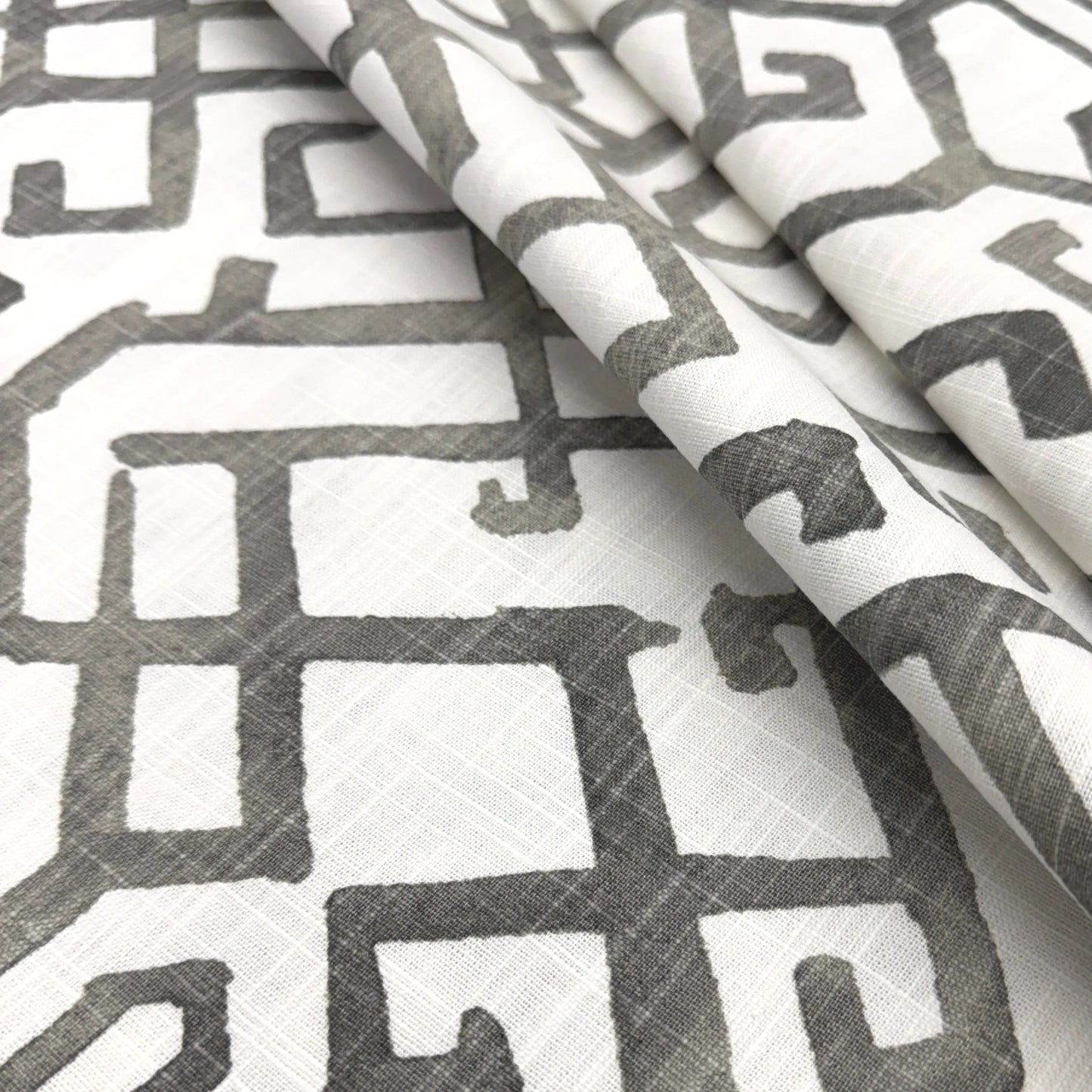 a close-up view of a fabric with a repeating pattern of geometric shapes in shades of gray and white.