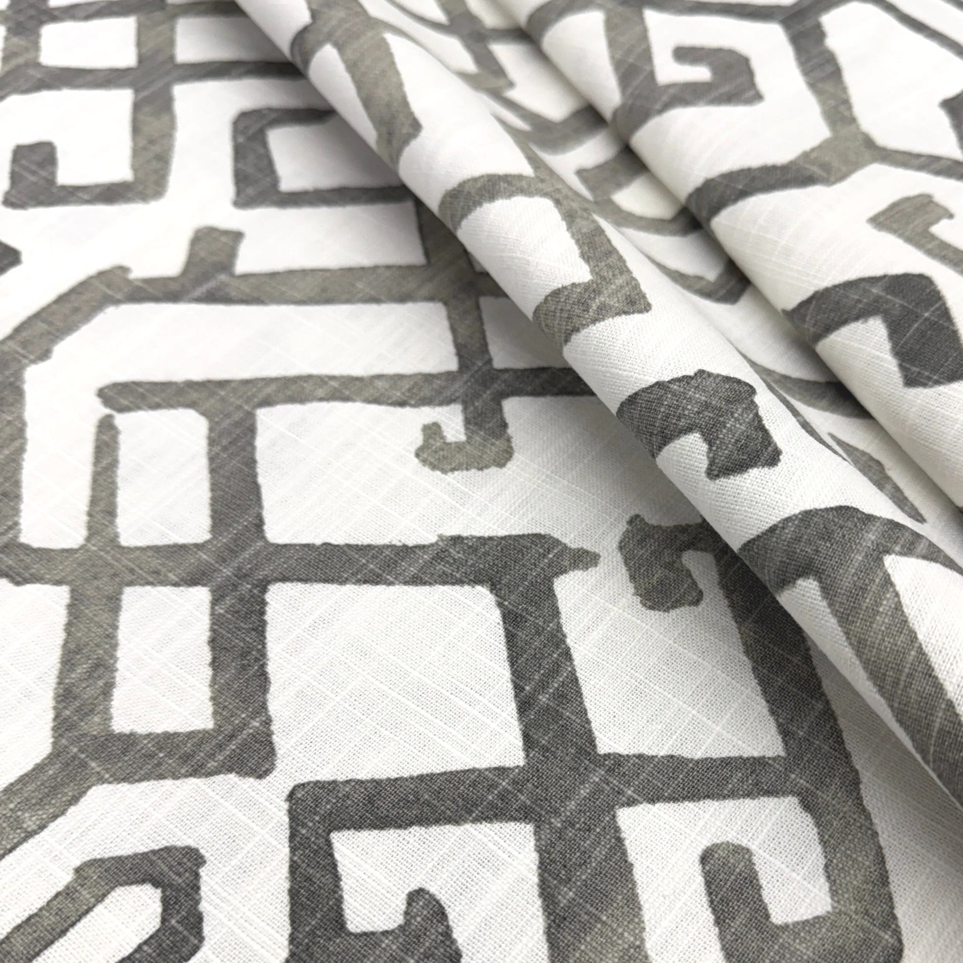 a close-up view of a fabric with a repeating pattern of geometric shapes in shades of gray and white.