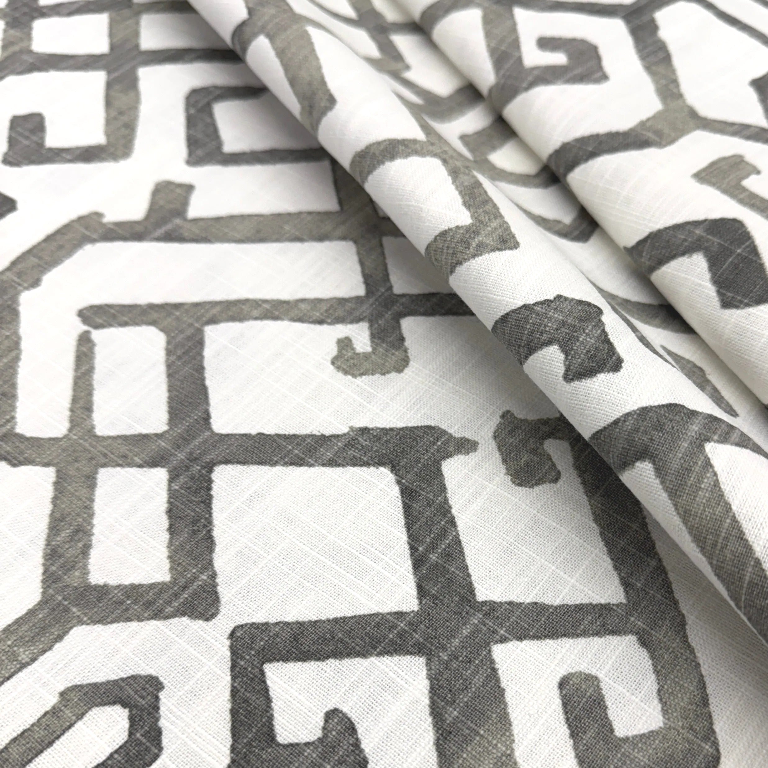 a close-up view of a fabric with a repeating pattern of geometric shapes in shades of gray and white.