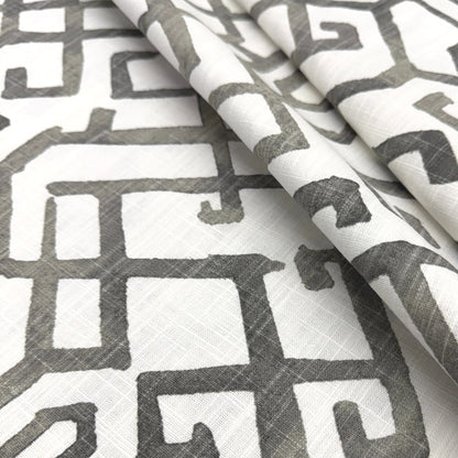 a close-up view of a fabric with a repeating pattern of geometric shapes in shades of gray and white.
