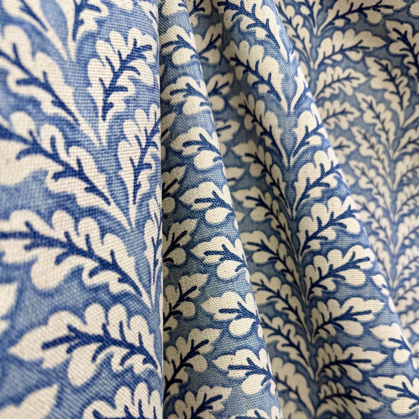 Blue and cream botanical vine fabric draped to show classic floral pattern and texture