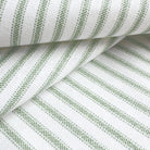 a close-up view of a fabric with a striped pattern in shades of green and white. The fabric appears to be folded or rolled, creating a visually interesting and textured surface.