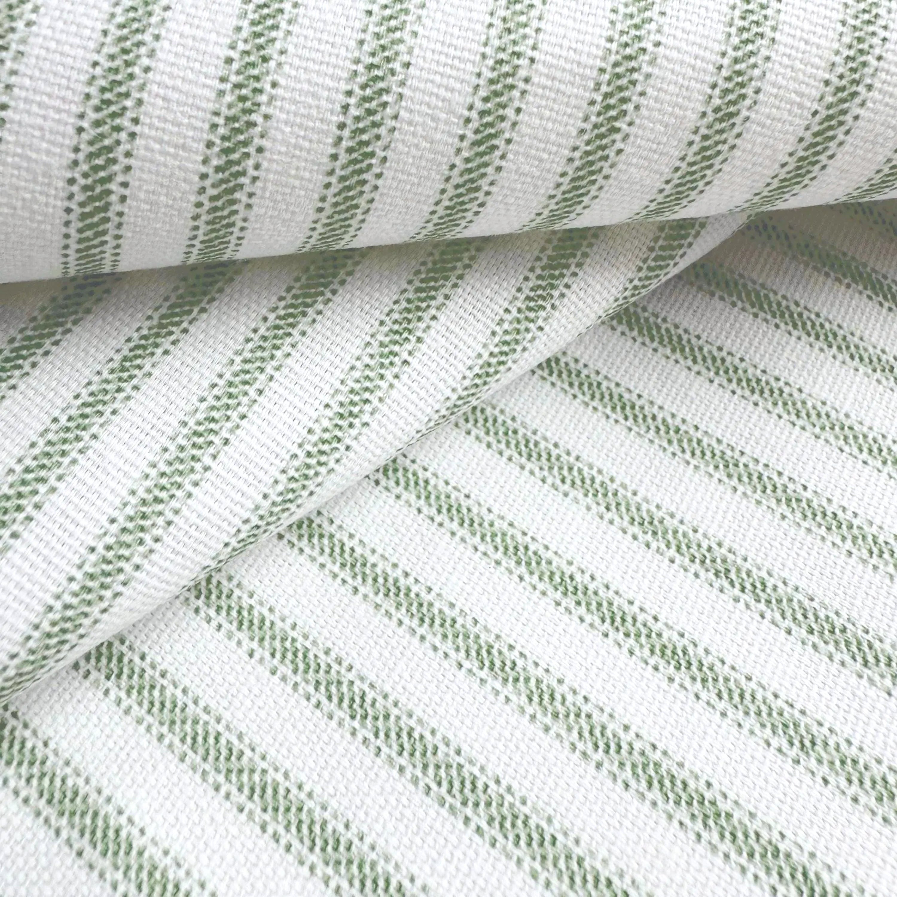 a close-up view of a fabric with a striped pattern in shades of green and white. The fabric appears to be folded or rolled, creating a visually interesting and textured surface.